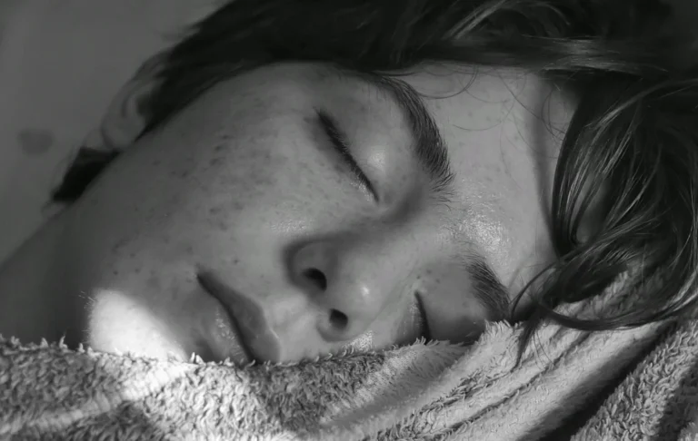 Black-and-white photo of a sleeping person used to illustrate how consistent bedtime timing can support better REM quality and a more stable body clock.